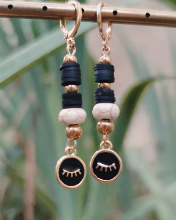Boucles d'oreilles pendantes avec des perles heishi noir , boules dorées et beige et un œil