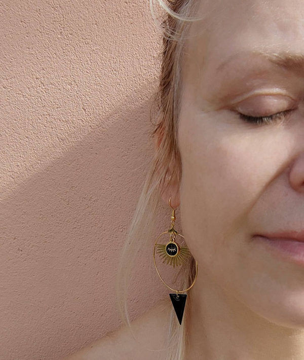 Boucles d'oreilles créoles dorées et son pendentif soleil avec un œil noir dessus et un triangle noir