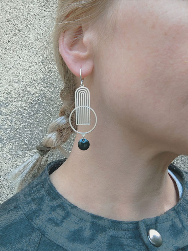 Boucles d'oreilles argent pendantes avec un sequin noir portées sur une oreille